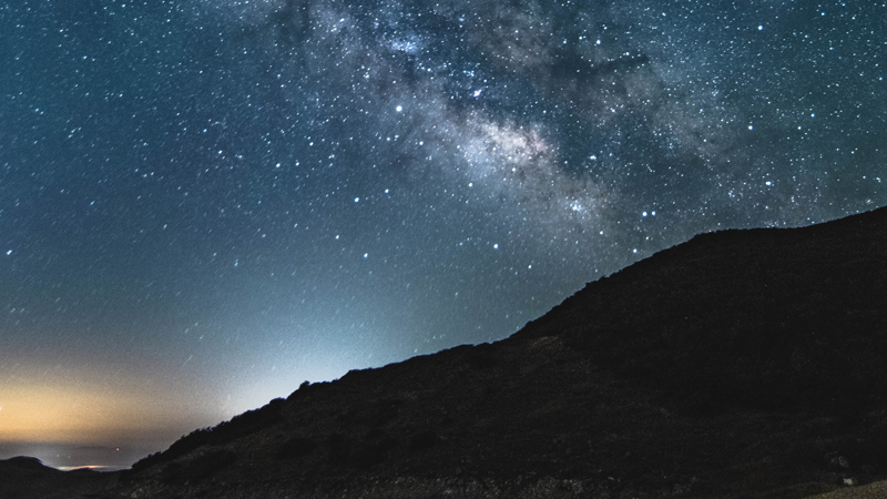 星が瞬く夜空と丘のシルエット